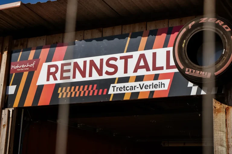 Schild Rennstall Tretcar-Verleih am Mohrenhof mit Zierteil eines Rennreifens