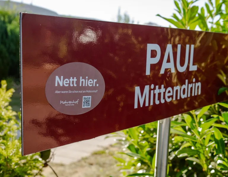 Der Nett hier Aufkleber angebracht auf dem roten Straßenschild Paul Mittendrin am Campingplatz