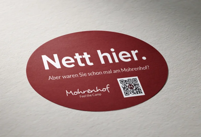 Produkt-Mockup des ovischen Mohrenhof Aufklebers Nett hier auf strukturiertem Untergrund