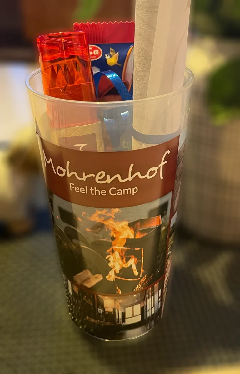 Transparenter Mohrenhof-Trinkbecher, gefüllt mit einem Feuerzeug, Snacks und einer Papierrolle